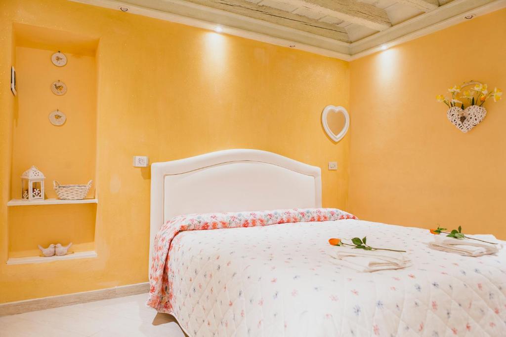 een slaapkamer met een wit bed en gele muren bij La Casa degli Uccellini in Lucca