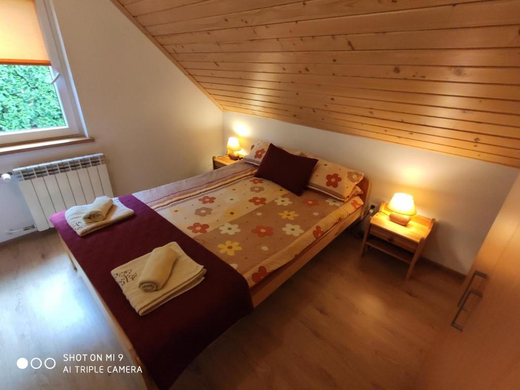 a small bedroom with a bed and a wooden ceiling at Domek u Lucy in Rabka-Zdrój