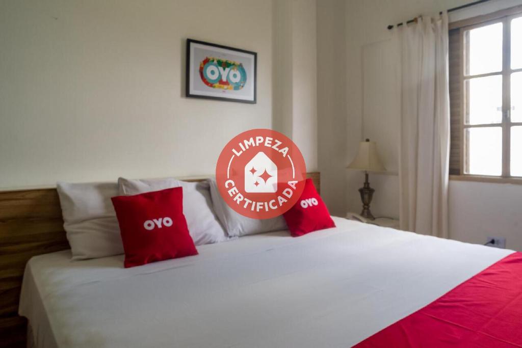 Schlafzimmer mit einem weißen Bett und roten Kissen in der Unterkunft Palace Hotel Campo Grande in Campo Grande