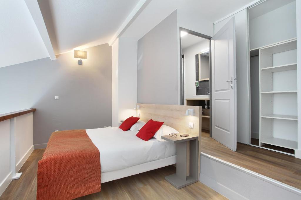 a small bedroom with a bed with red pillows at Odalys City Aix en Provence Le Clos de la Chartreuse in Aix-en-Provence