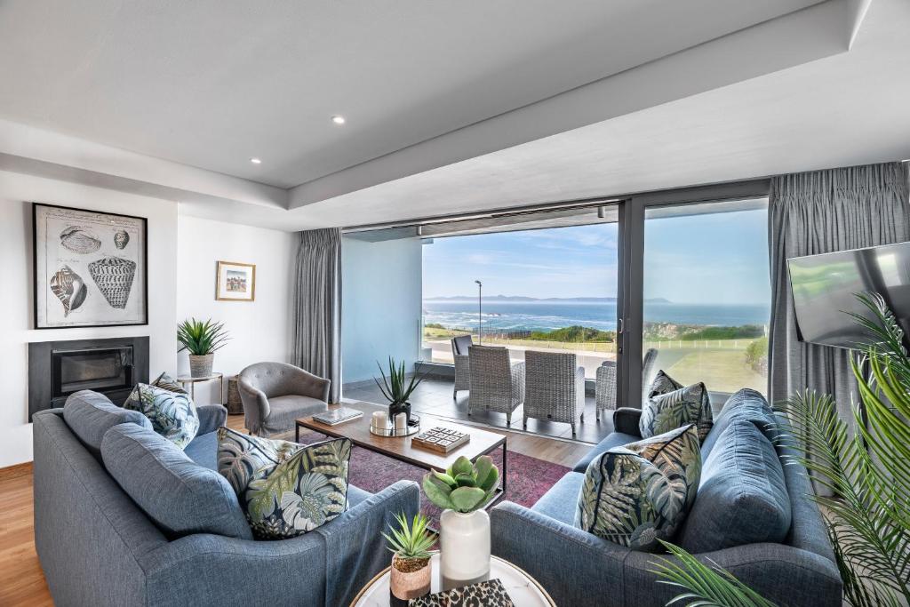 a living room with blue couches and a large window at 17 Marine - 3Bedroom Sea-Facing Apt101 in Hermanus