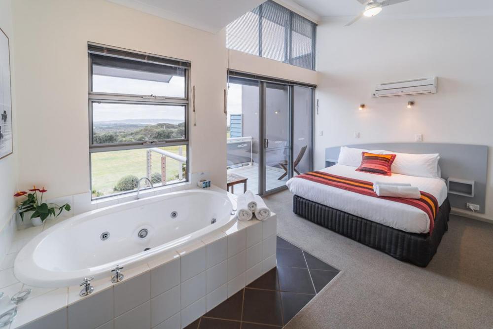 a bedroom with a bed and a tub in a room at Cosy Corner Sea View Apartments in Albany