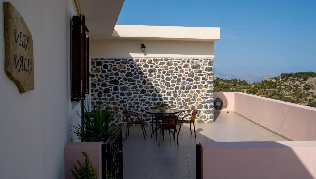 balcón con mesa, sillas y pared en Villa Valia- Relaxation and Cretan hospitality, en Ierápetra