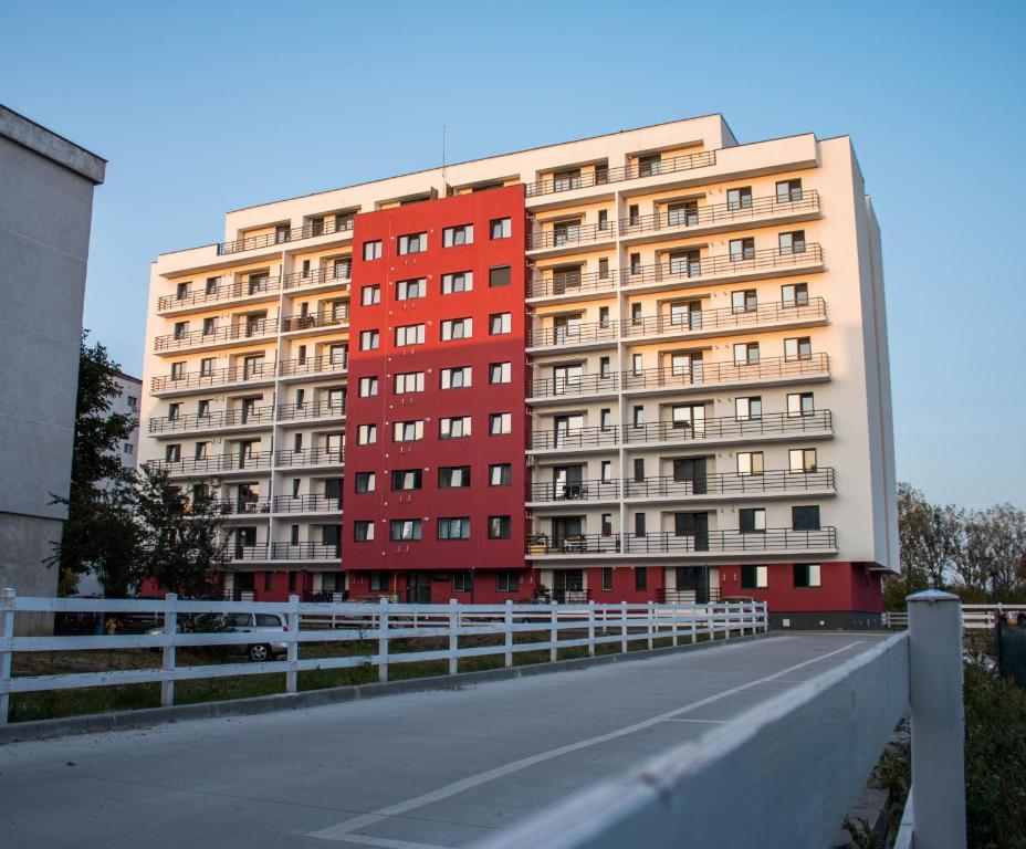 a red building with a white fence next to a road at Dream Arena Apartment in Bacău