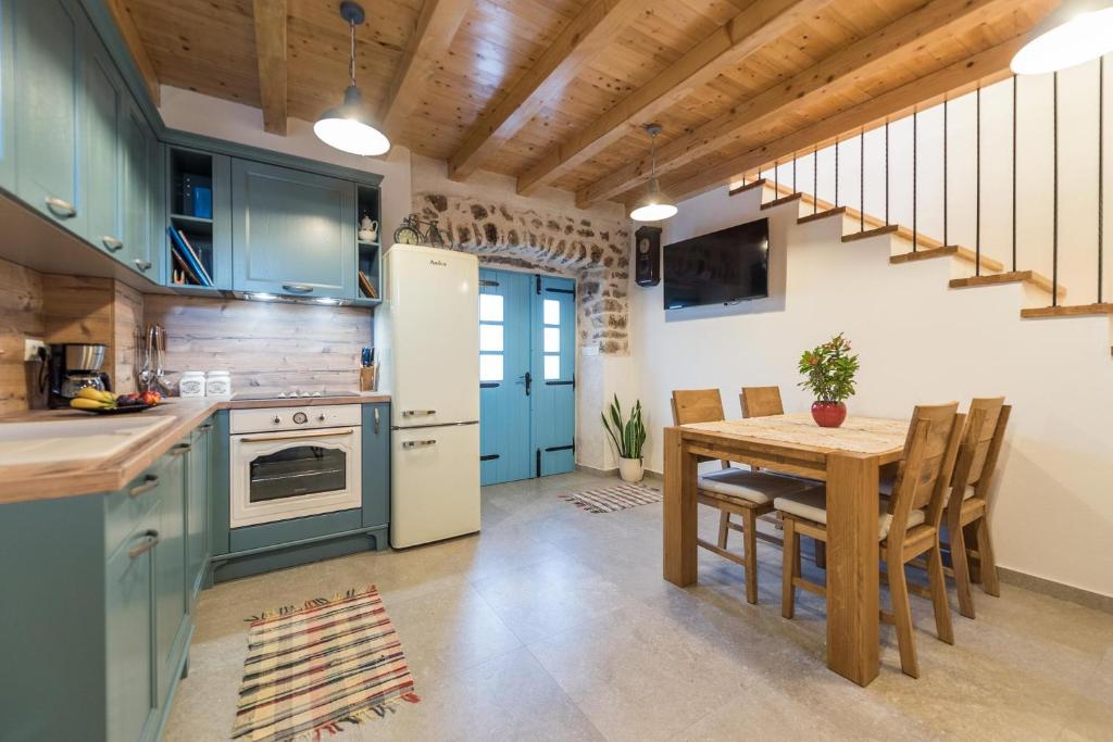 eine Küche mit blauen Schränken und einem Tisch mit einem Esszimmer in der Unterkunft Holiday Home Lipa Naša in Neviđane