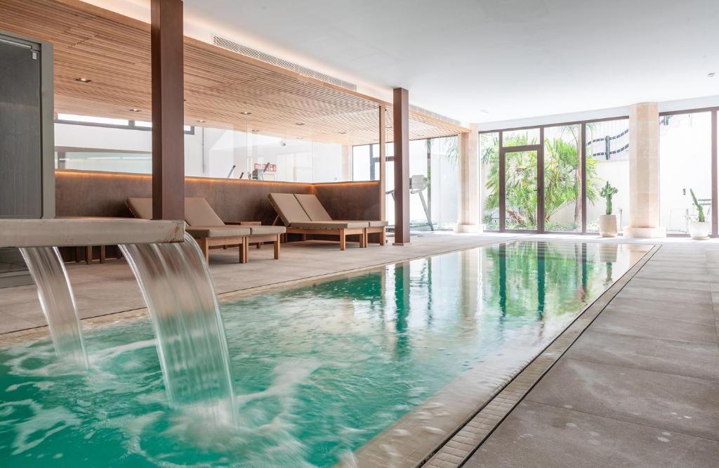 a swimming pool with a fountain in a building at Ynaira hotel & Spa in Ariany
