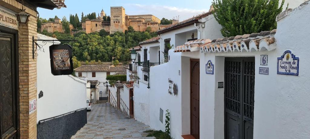een straat met witte gebouwen met een kasteel op de achtergrond bij Carmen de Alaïa By Florentia Homes in Granada