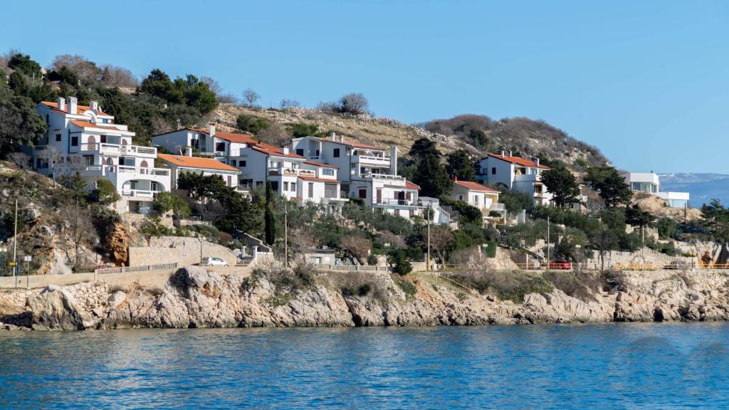 a group of houses on a hill next to the water at Apartments Katarina in Baška