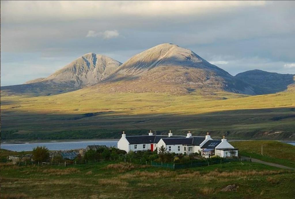 a house on a hill with mountains in the background at Charming quirky coastal Cottage Port Ellen in Port Ellen