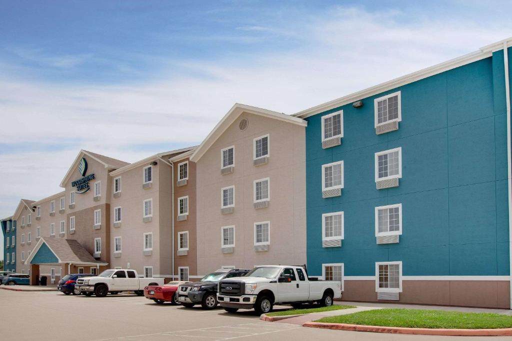 テキサスシティにあるWoodSpring Suites Texas Cityの駐車場車を停めた大きな建物