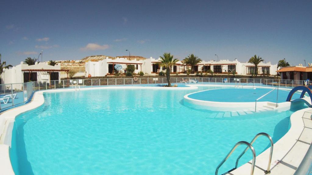 uma grande piscina com água azul num resort em Castillo Sol Bungalow em Caleta De Fuste