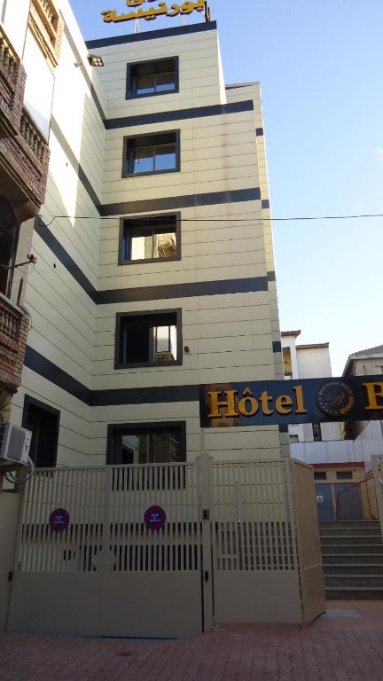 un bâtiment d'hôtel avec une clôture devant lui dans l'établissement Hotel Bournissa, à Rouiba