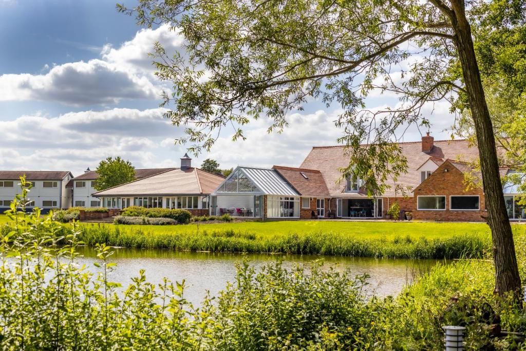 uma casa com um lago em frente em Kingfisher Hotel, Golf and Country Club em Milton Keynes