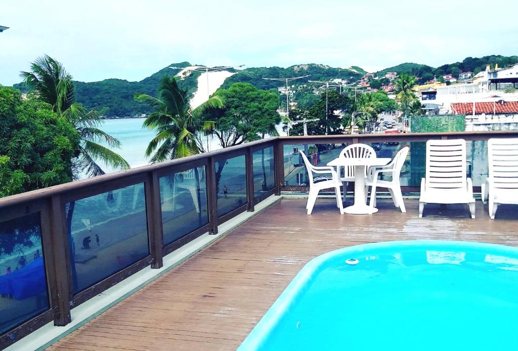 Bella Natal Praia Hotel في ناتال: بلكونه مع طاوله وكراسي ومسبح