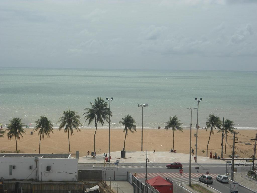 a view of a beach with palm trees and the ocean at Atlântico Tambaú Home Service in João Pessoa