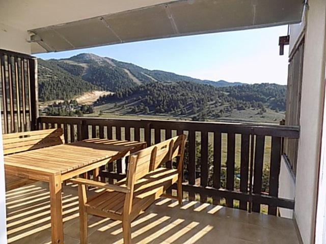 una mesa de madera y sillas en un balcón con vistas en Les Fougères, en Gréolières les Neiges