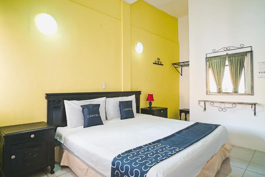 1 dormitorio con 1 cama grande y paredes azules y amarillas en Capital O Los Angeles, Chiapa de Corzo, en Chiapa de Corzo