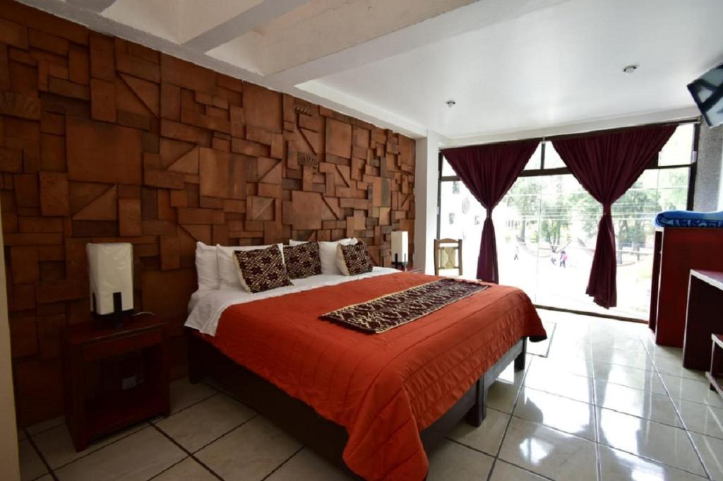 1 dormitorio con cama y pared de piedra en Hotel Boutique Acocalli, en San Juan Teotihuacán