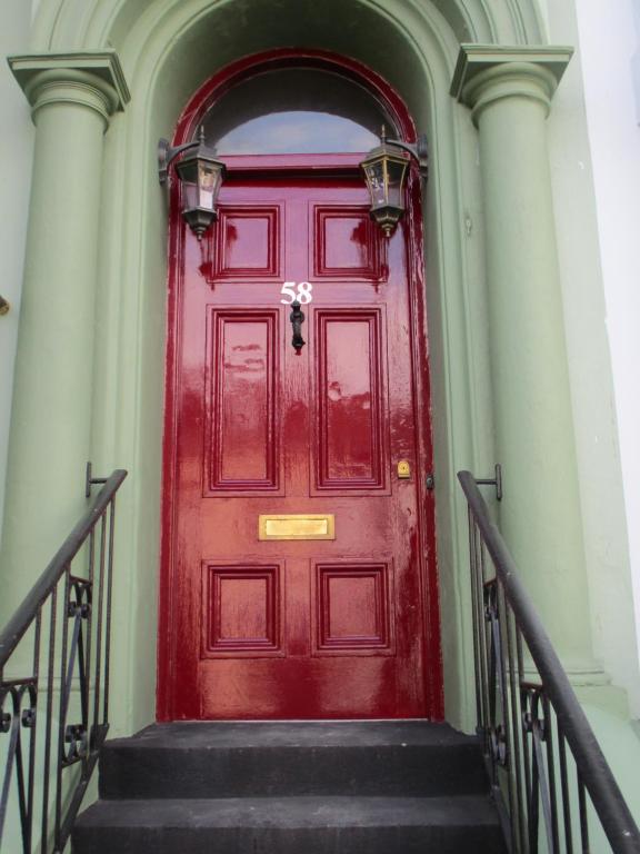 a red door on a building with stairs at Cranborne Guest Accommodation Exclusively for Adults in Torquay