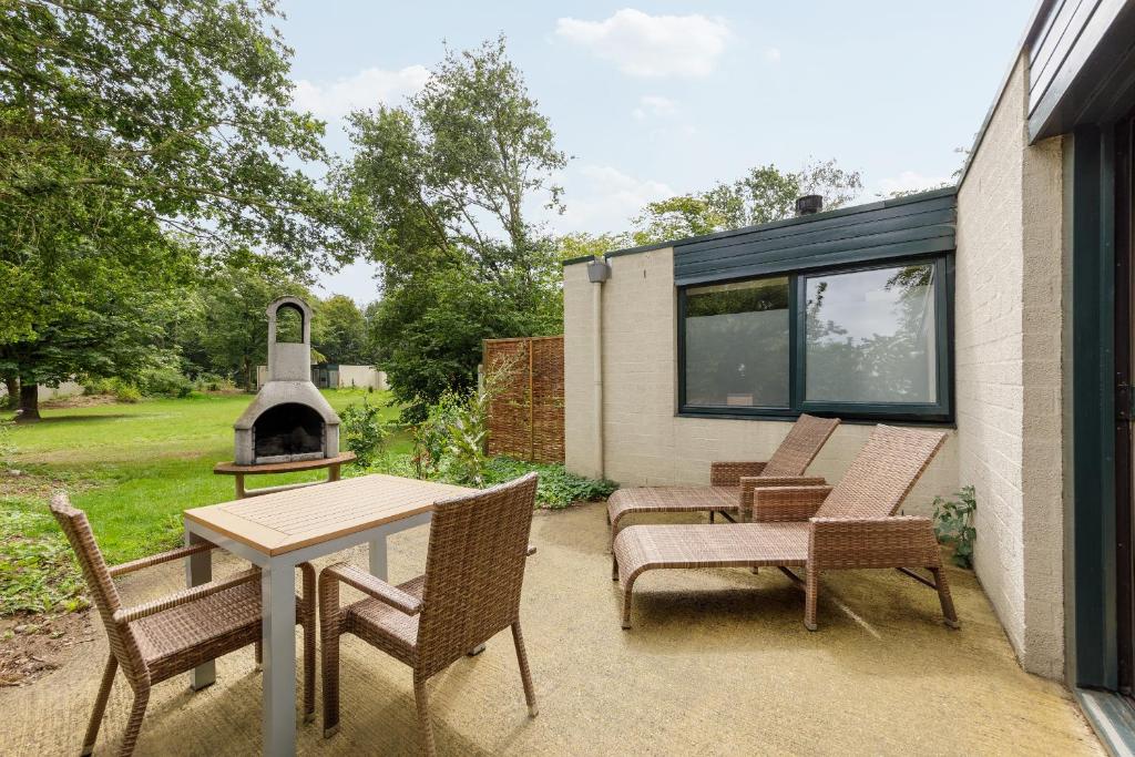 d'une terrasse avec une table, des chaises et une cheminée. dans l'établissement Center Parcs Heijderbos Limburg-Weeze, à Heijen