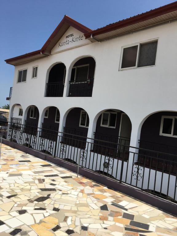 a white building with black doors and a stone floor at Kunta Kinte Hotel in Accra