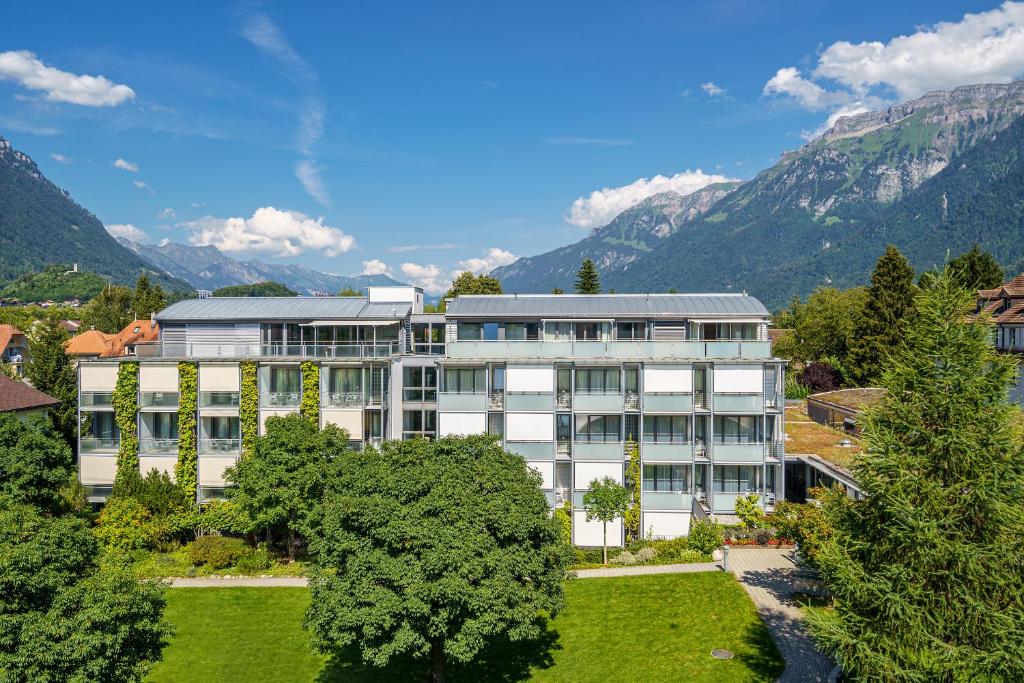 Bild eines Gebäudes mit Bergen im Hintergrund in der Unterkunft Hotel Artos Interlaken in Interlaken