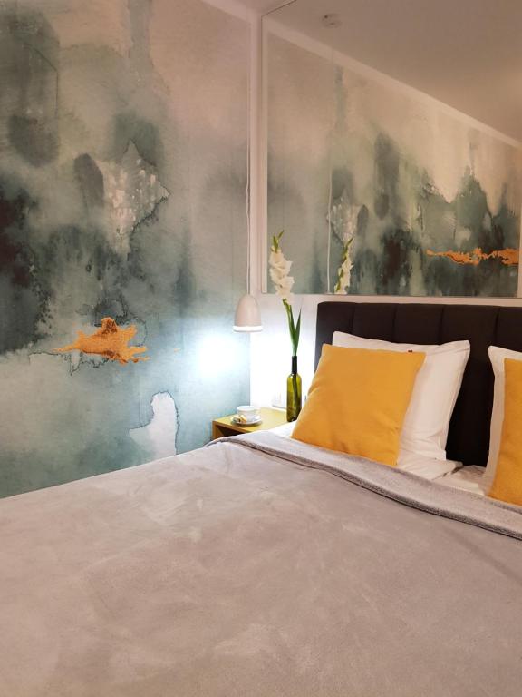 ein Schlafzimmer mit einem großen Bett mit gelben Kissen in der Unterkunft Old Motława Mirror Apartment in Danzig