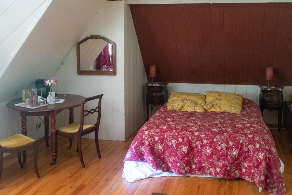 a bedroom with a bed and a table in a attic at Le clos des mûriers in Hautot-sur-Mer