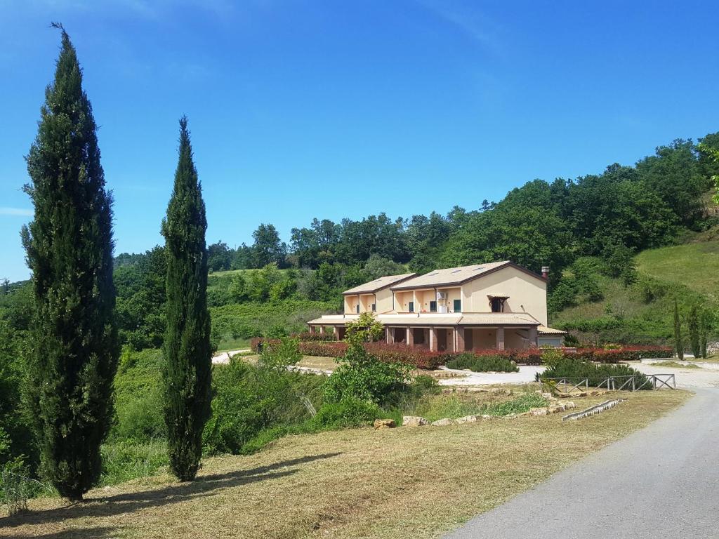 una casa su una collina con alberi e una strada di Saturnia Tuscany Country House a Saturnia