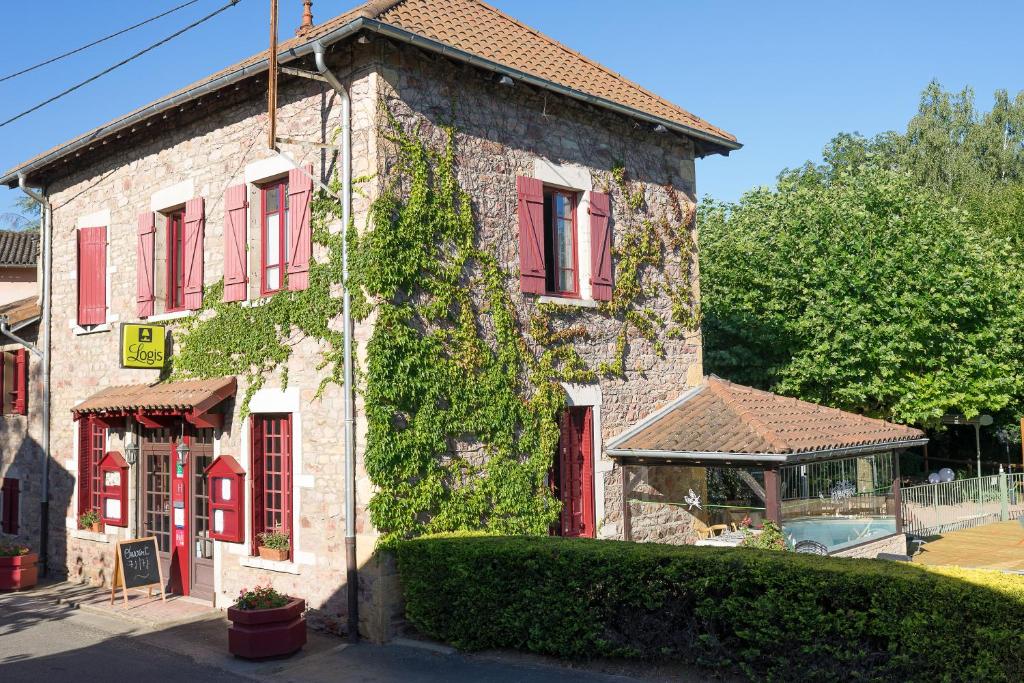 un edificio con persianas rojas y hiedra. en Hôtel Restaurant Le Moulin de Saint Verand en Saint-Vérand