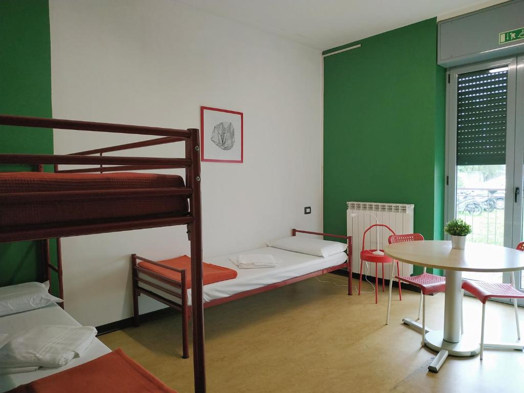 サロンノにあるOstello di Saronno - Malpensa Hostelの二段ベッド2台、テーブル、テーブルが備わる客室です。