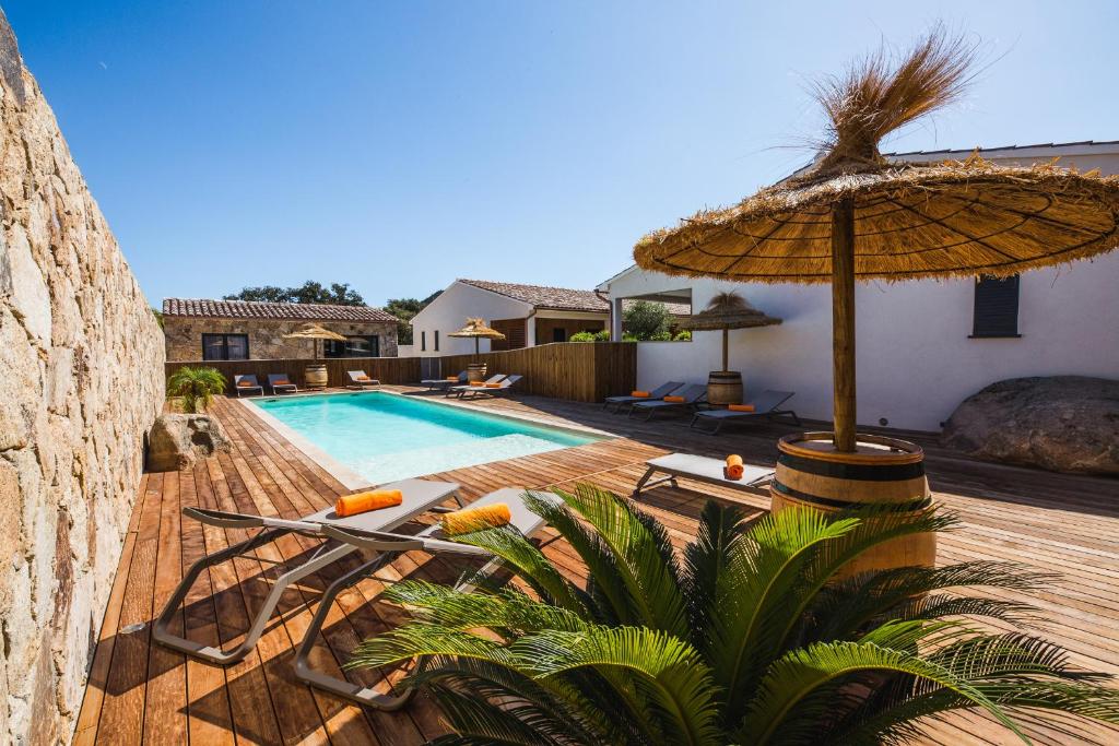 - une piscine avec un parasol et des chaises dans l'établissement Petra d'Oro Villa Palombaggia, à Porto-Vecchio