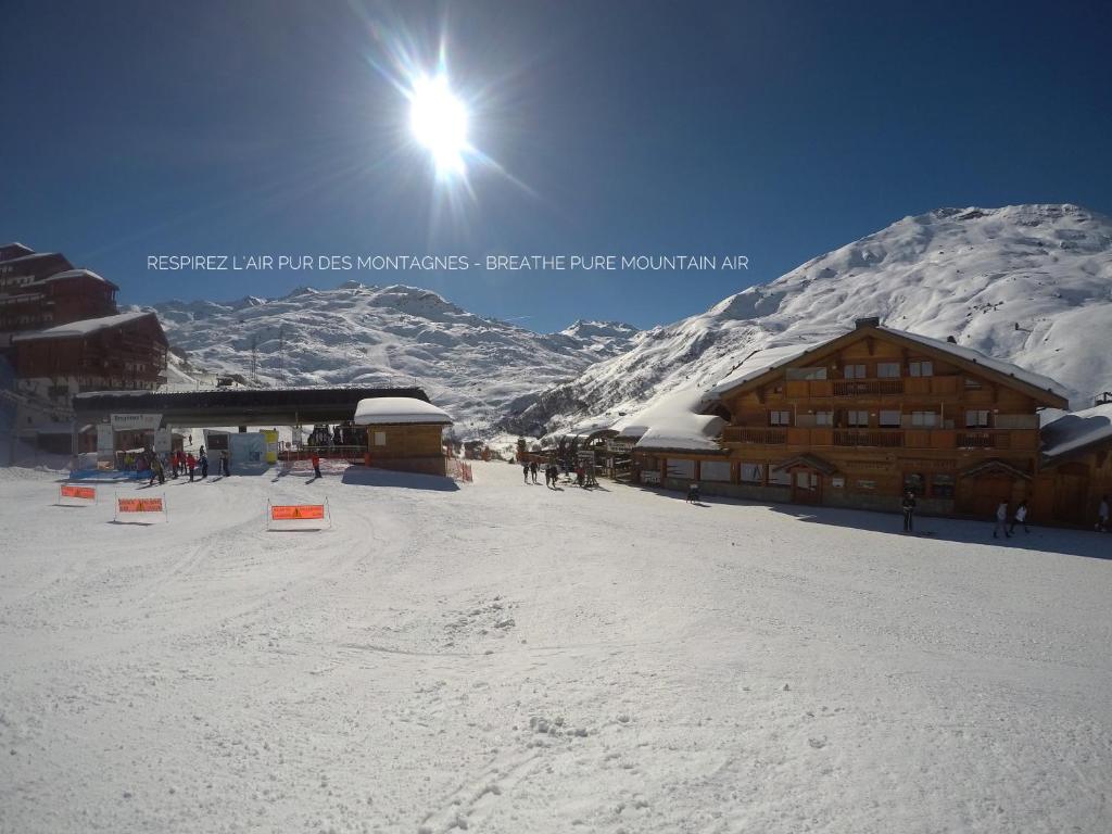 un lodge de ski avec une montagne enneigée en arrière-plan dans l'établissement L'Isatis Chalet Hotel, aux Menuires
