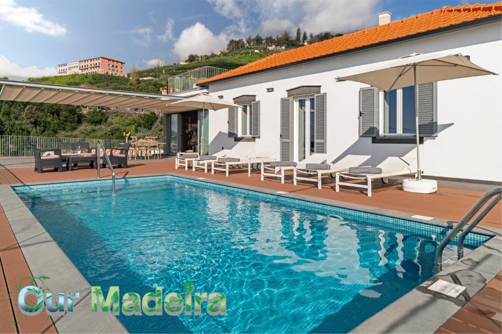 a swimming pool in front of a house at OurMadeira - Vila da Portada, character in Funchal