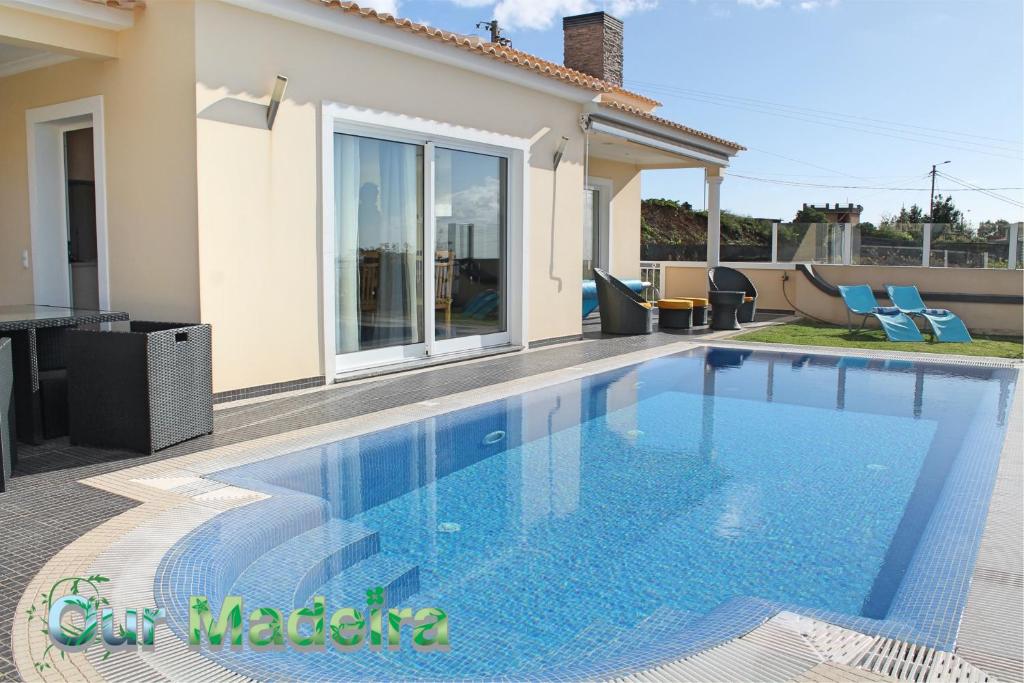 a swimming pool in front of a house at OurMadeira - Villa Dilis, informal in Calheta