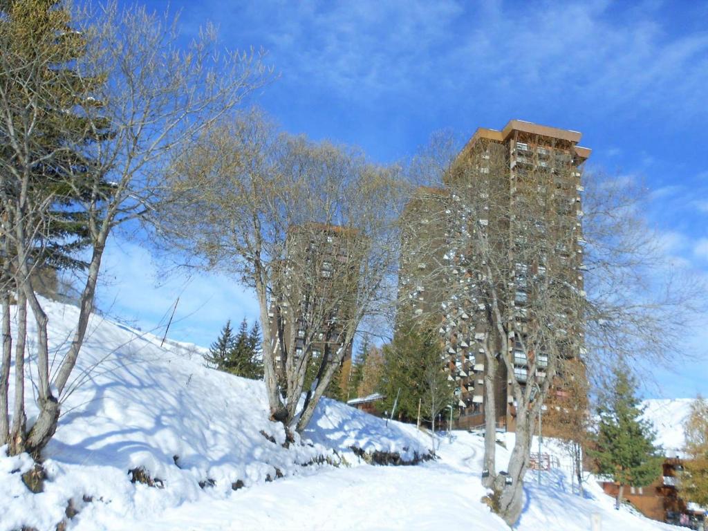 eine Gruppe von Bäumen im Schnee mit Gebäuden in der Unterkunft travelski home classic - Résidence Soyouz in Le Corbier