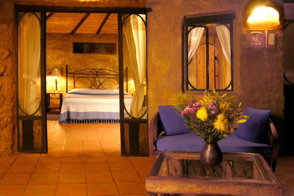 um quarto com uma cama e uma mesa com um vaso de flores em Hotel Valle Místico em Tepoztlán