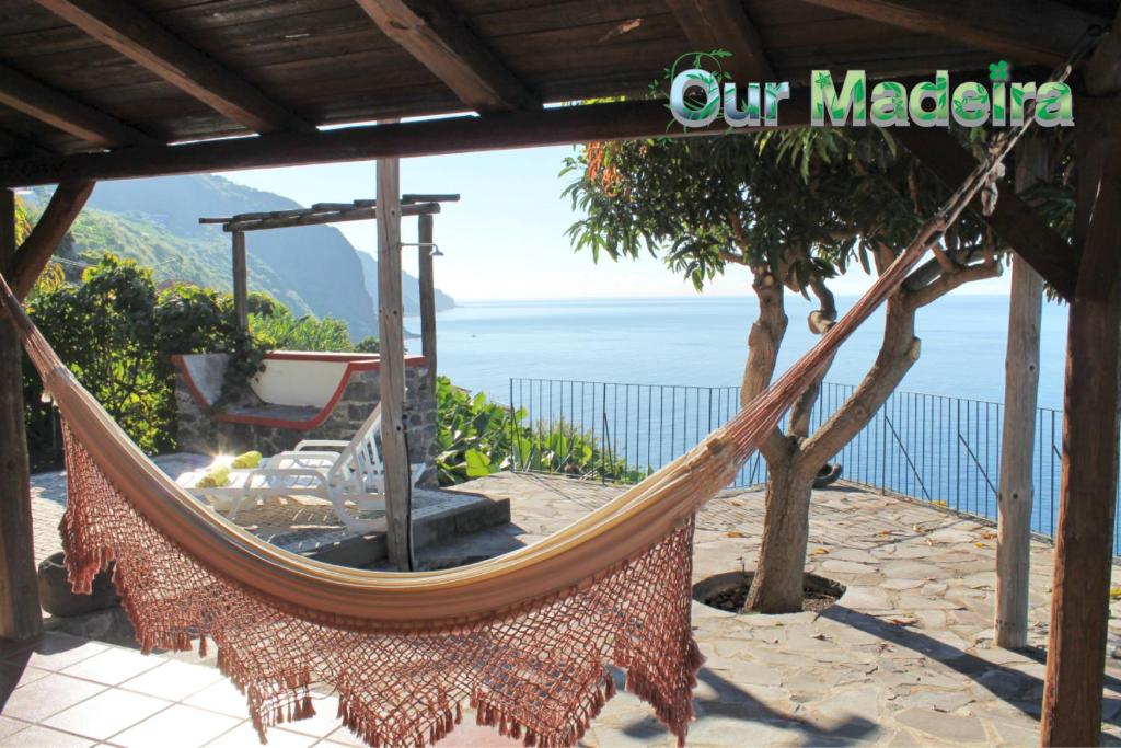 a hammock on a patio with a view of the ocean at OurMadeira - Stonecliff Cottage, countryside retreat in Calheta