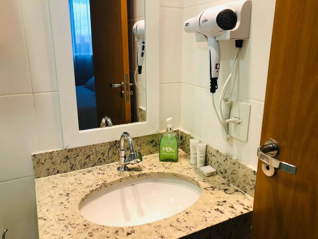 La salle de bains est pourvue d'un lavabo, d'un distributeur de savon et d'un miroir. dans l'établissement 410 Everest Flat Service, à Caldas Novas