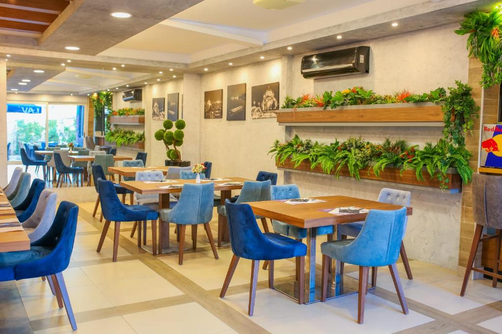 un restaurante con mesas de madera y sillas azules en Hotel City Code Vizura garni RENEW en Belgrado