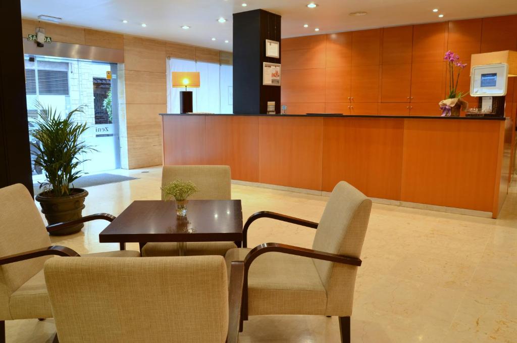 a lobby with a table and chairs and a counter at Zenit Málaga in Málaga
