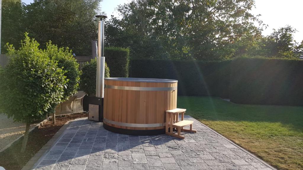 a wooden barrel sitting on a patio with a bench at Casa-Anja in Zingem