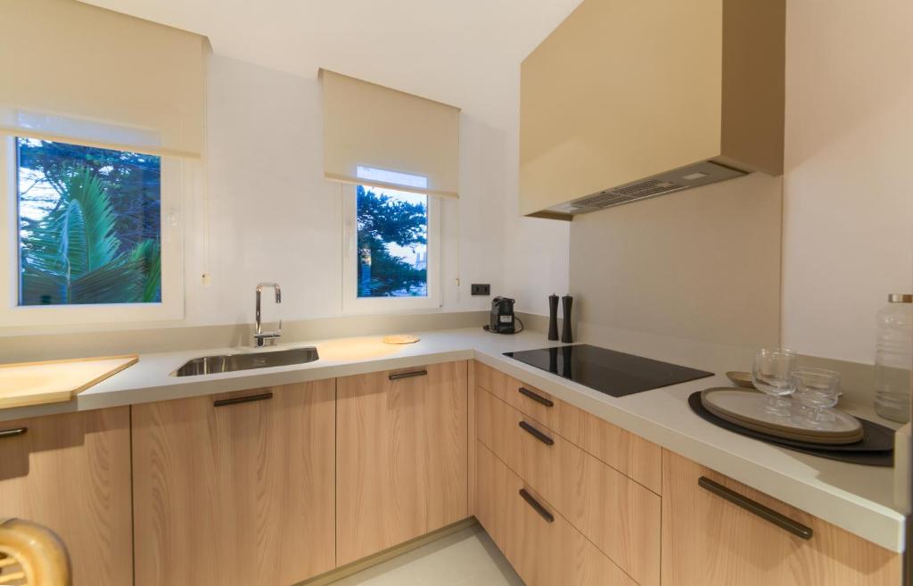 a kitchen with wooden cabinets and a sink and a window at Villas Flamenco Beach Conil in Conil de la Frontera