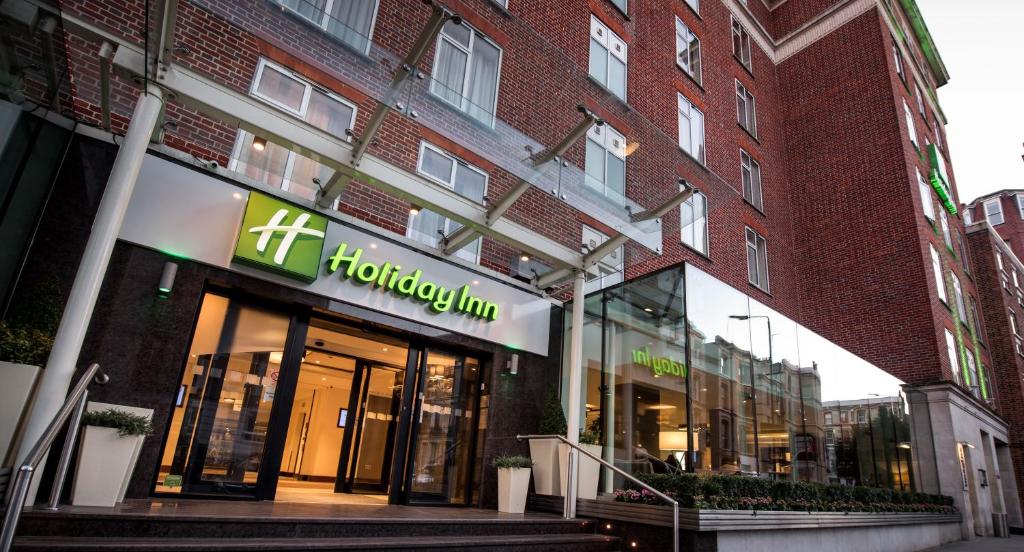 倫敦的住宿－Holiday Inn London Kensington High St., an IHG Hotel，砖楼前的商店,上面有标志