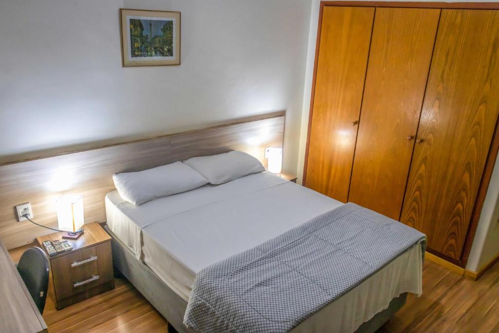 1 dormitorio con 1 cama grande y armario de madera en Hotel Portucali, en Ribeirão Preto