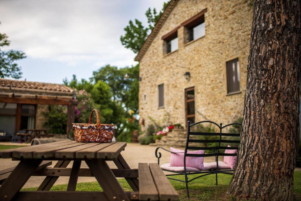 una mesa de picnic y un banco junto a un edificio en Mas Ombravella, en Mieres