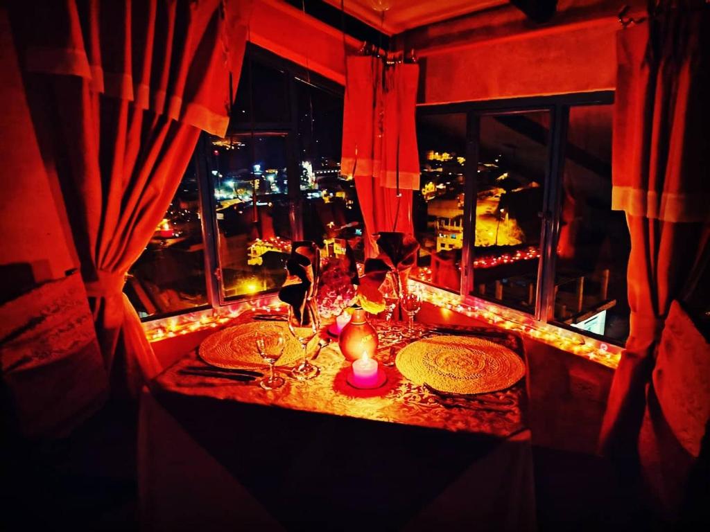 een tafel met borden en kaarsen in een kamer met een raam bij Hotel Achik Wasi in Saraguro