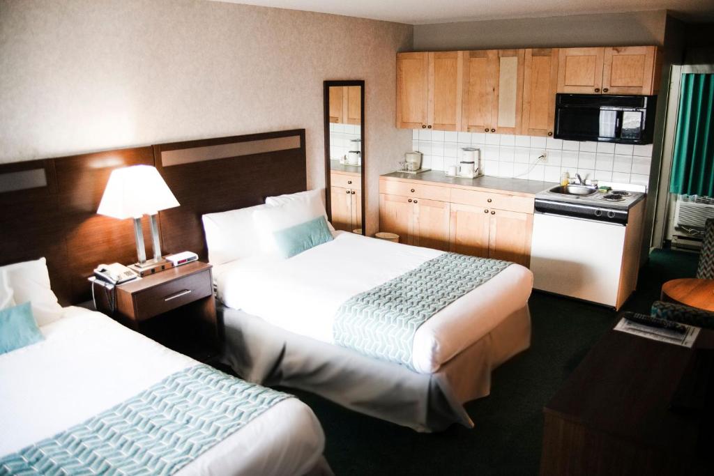 Habitación de hotel con 2 camas y cocina en Ramada by Wyndham, en Quesnel
