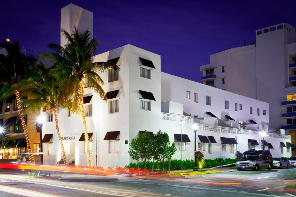 a white building with palm trees in front of a street at Blanc Kara- Adults Only in Miami Beach
