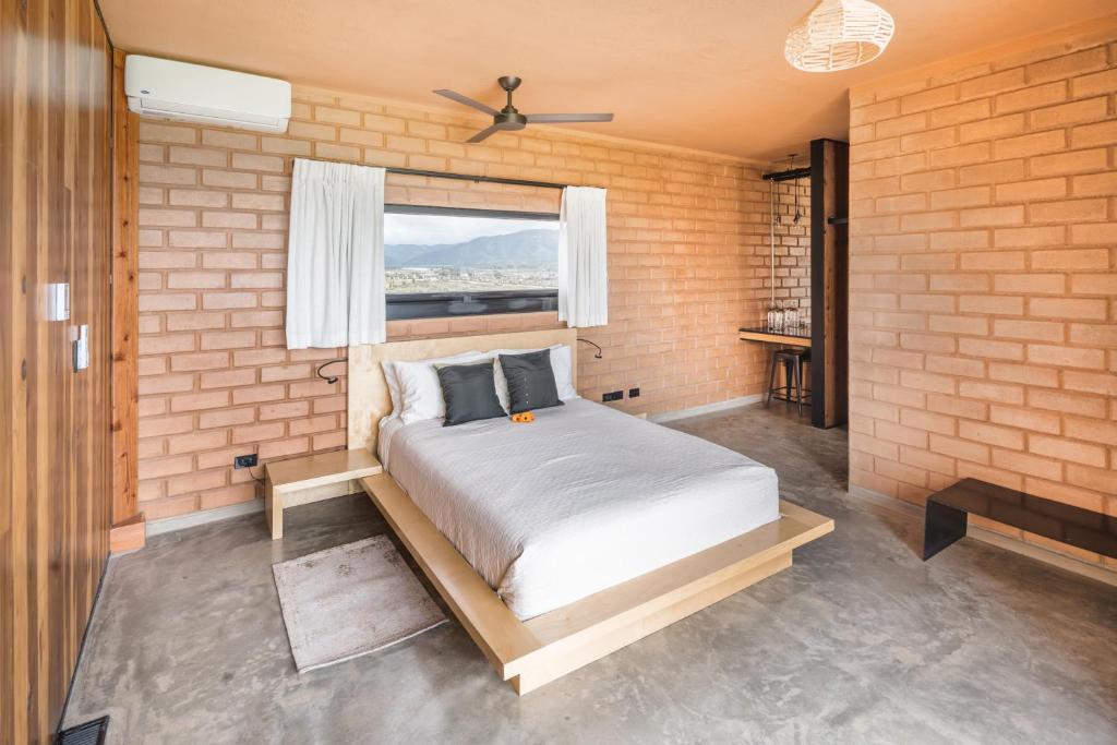 1 dormitorio con 1 cama en una pared de ladrillo en Santulan en Valle de Guadalupe